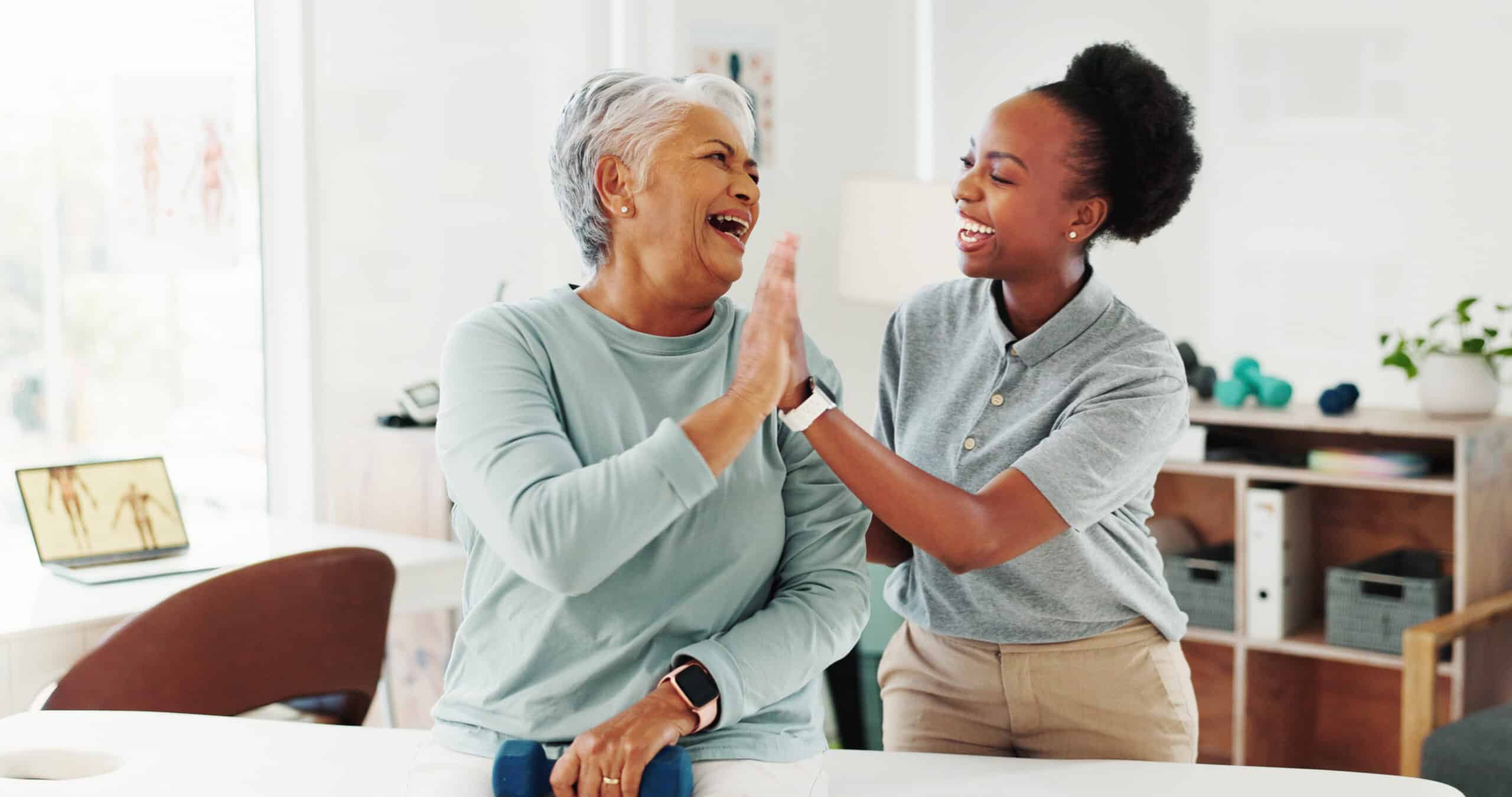 older woman with a home health aide high-fiving