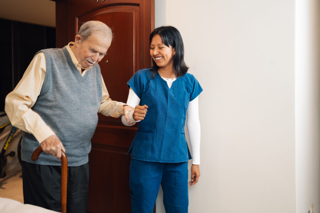 home care aide helping an older man with a cane